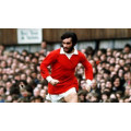 Photo d'époque de George Best sur le terrain de jeu avec le maillot du Manchester United des années 70
